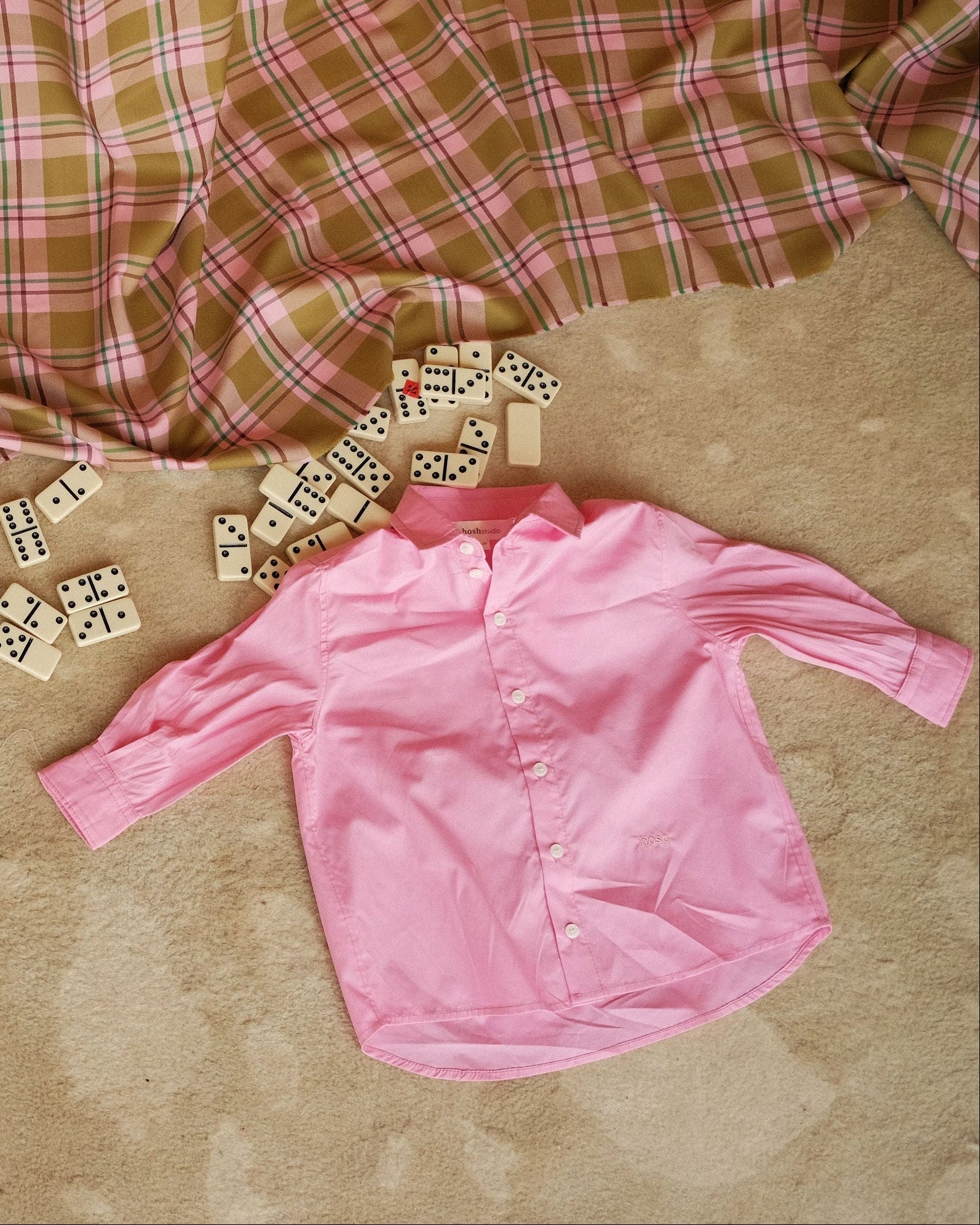 Pink shirt and dominoes on a checkered fabric background