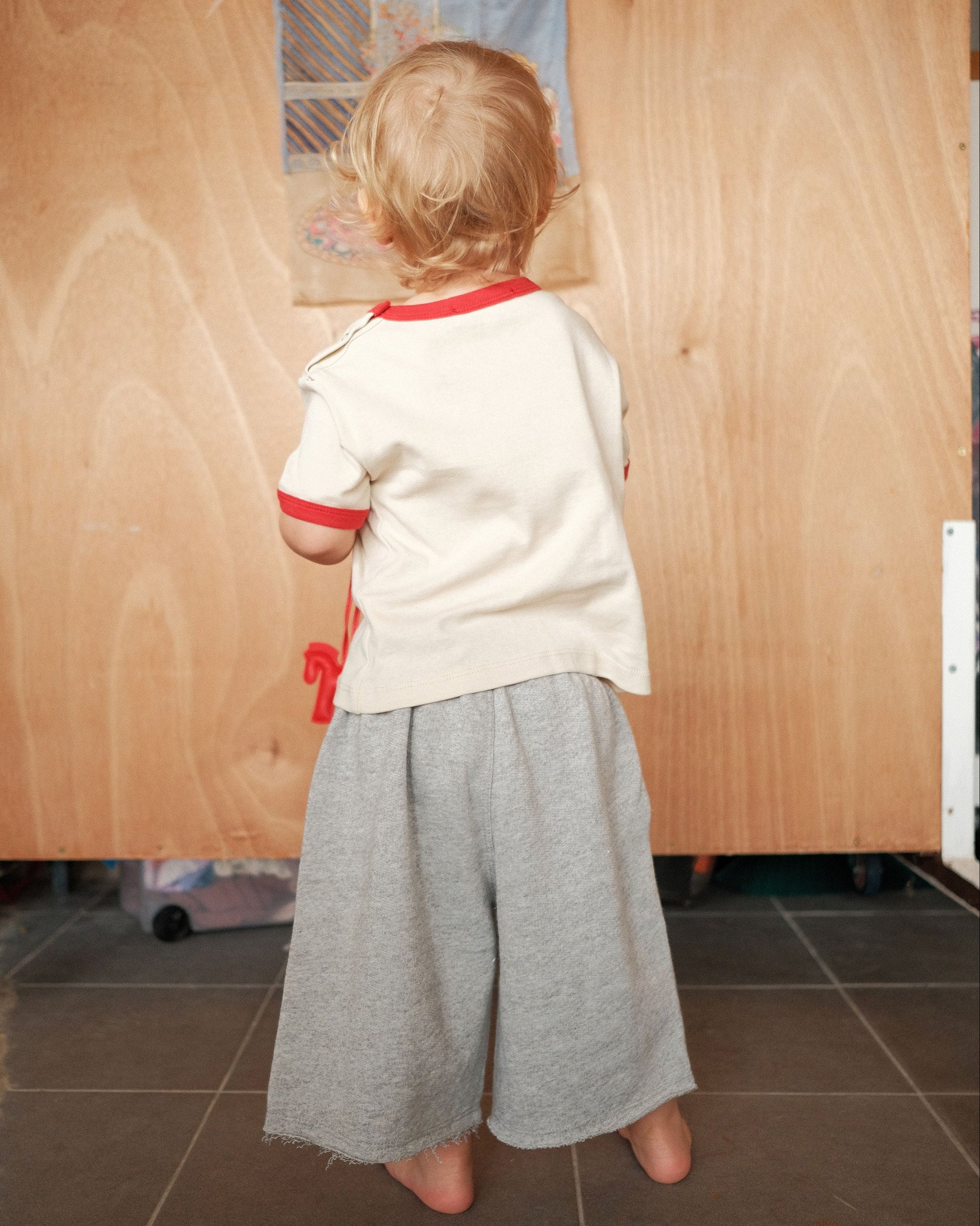 Child standing in front of a wooden panel with drawings on it