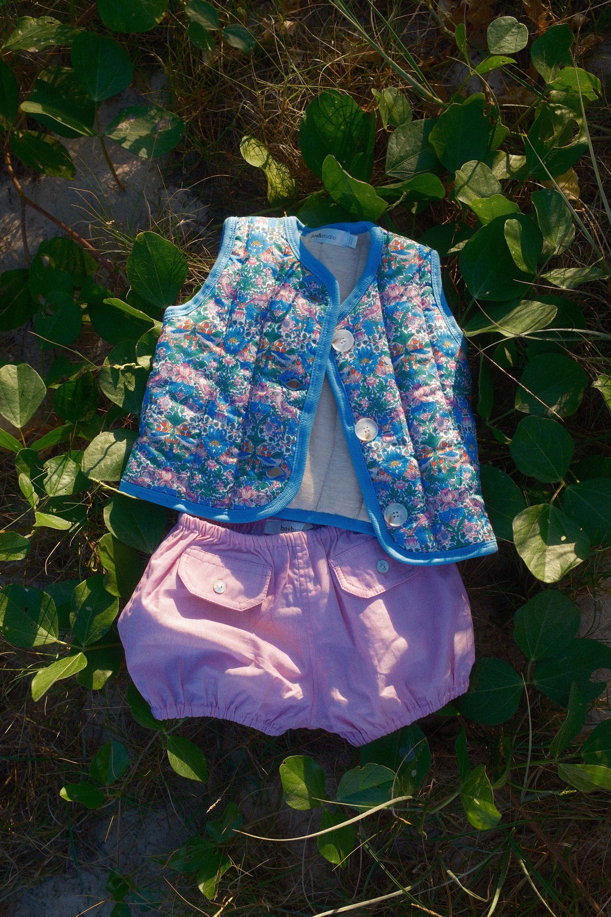 Floral jacket and pink shorts on green leaves