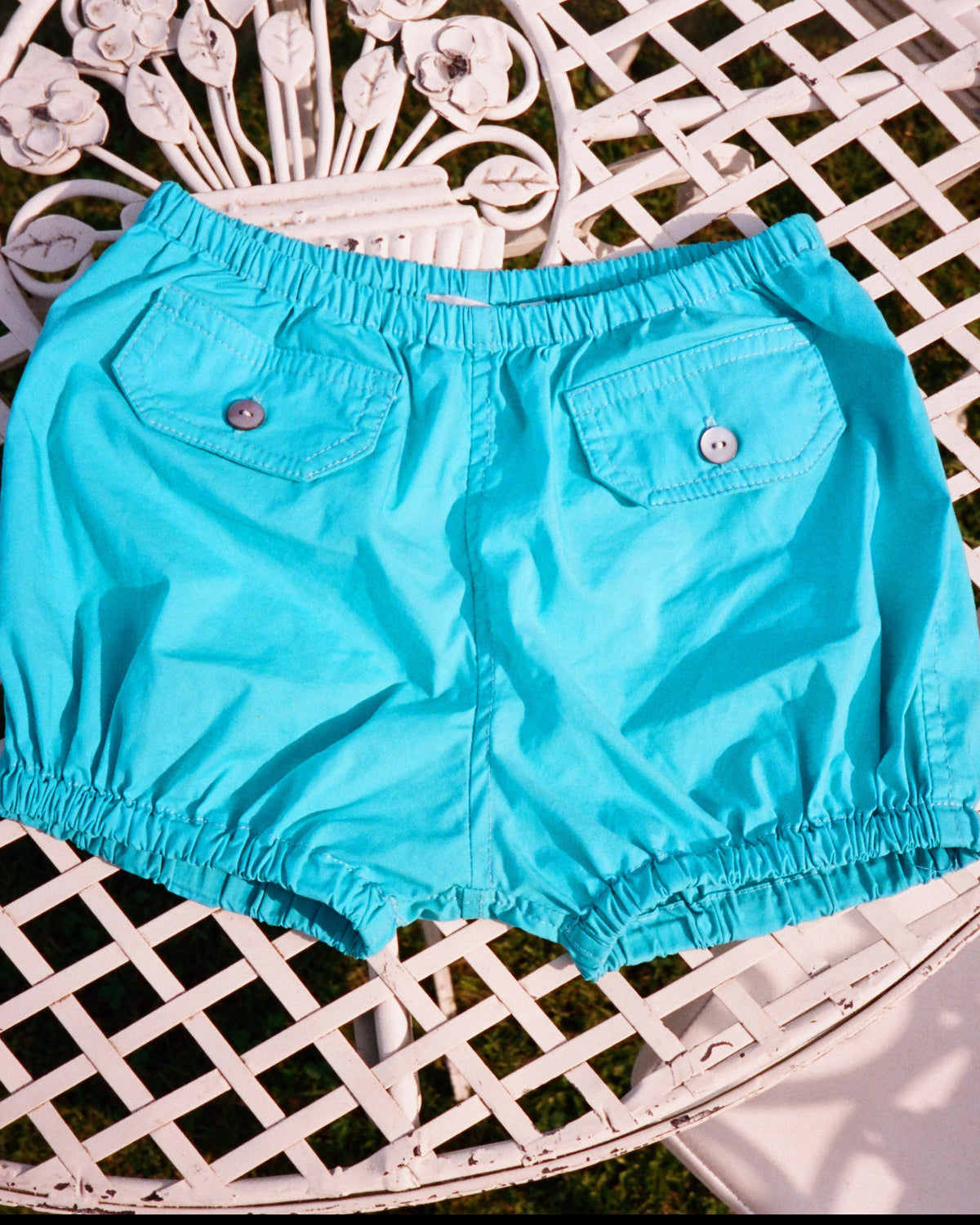 Turquoise shorts on a white metal table outdoors
