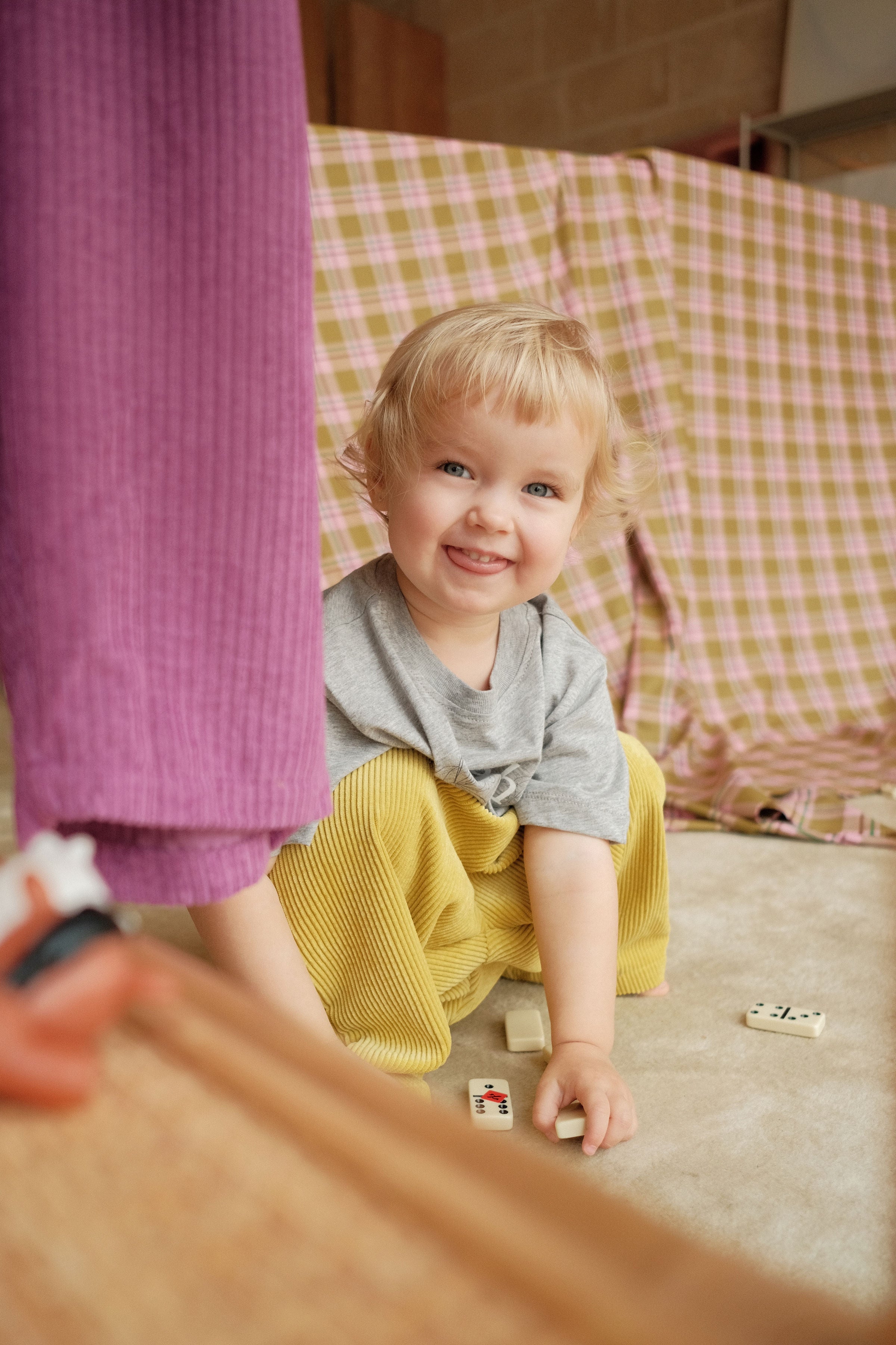 Child sitting on the floor with colorful cloths in the background