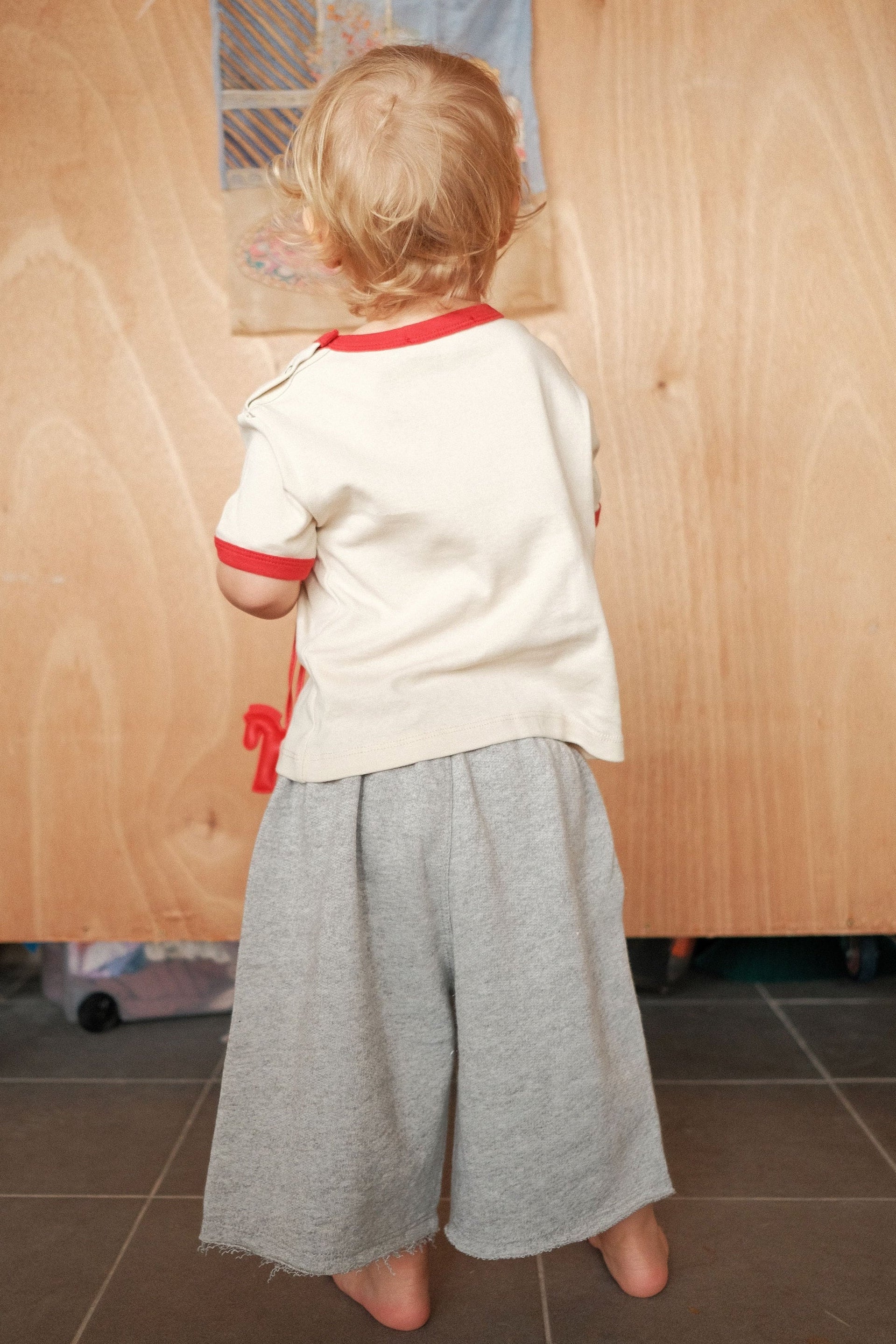 Child standing in front of a wooden panel with drawings on it