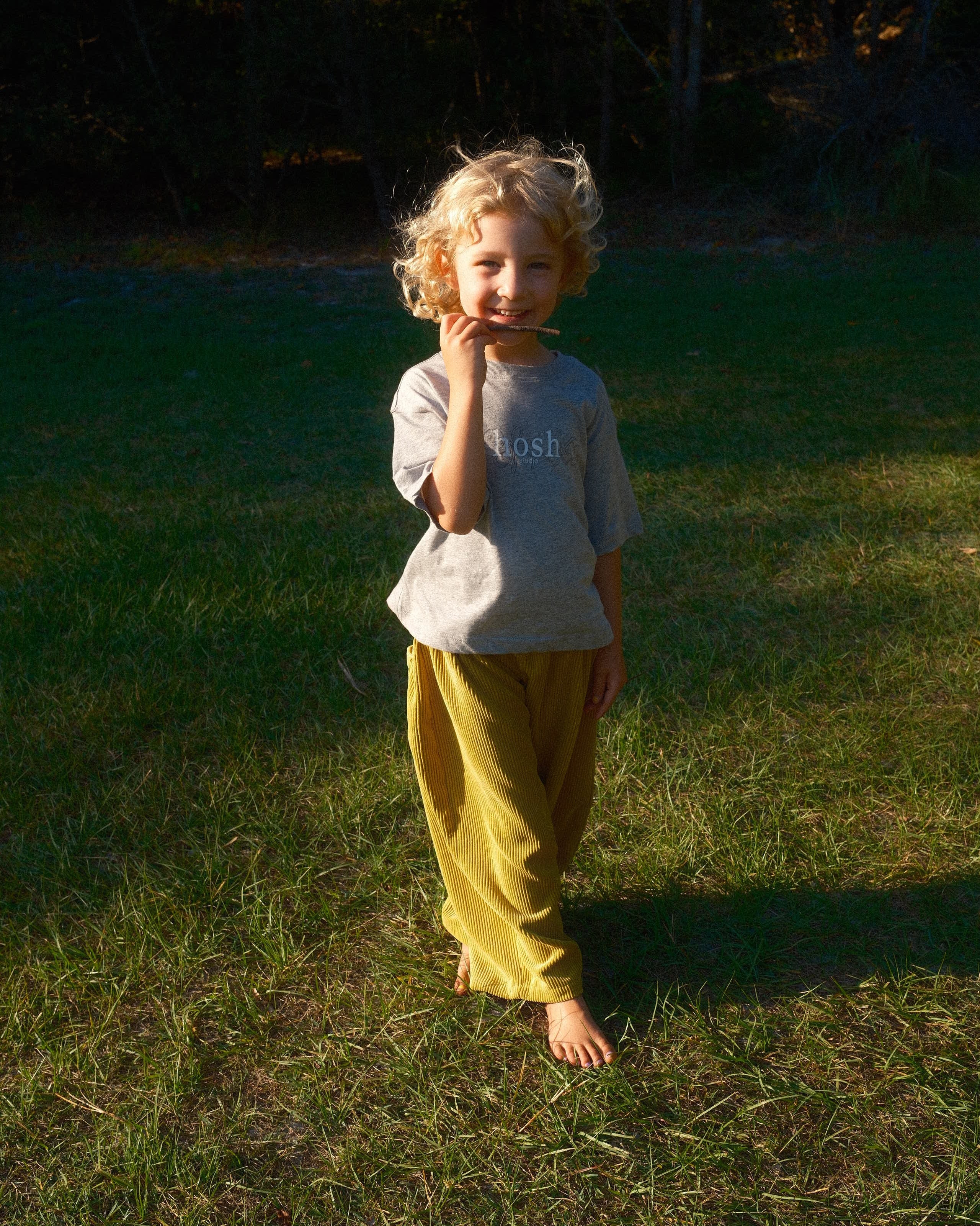Child in a yellow dress standing on grass, viewed from above
