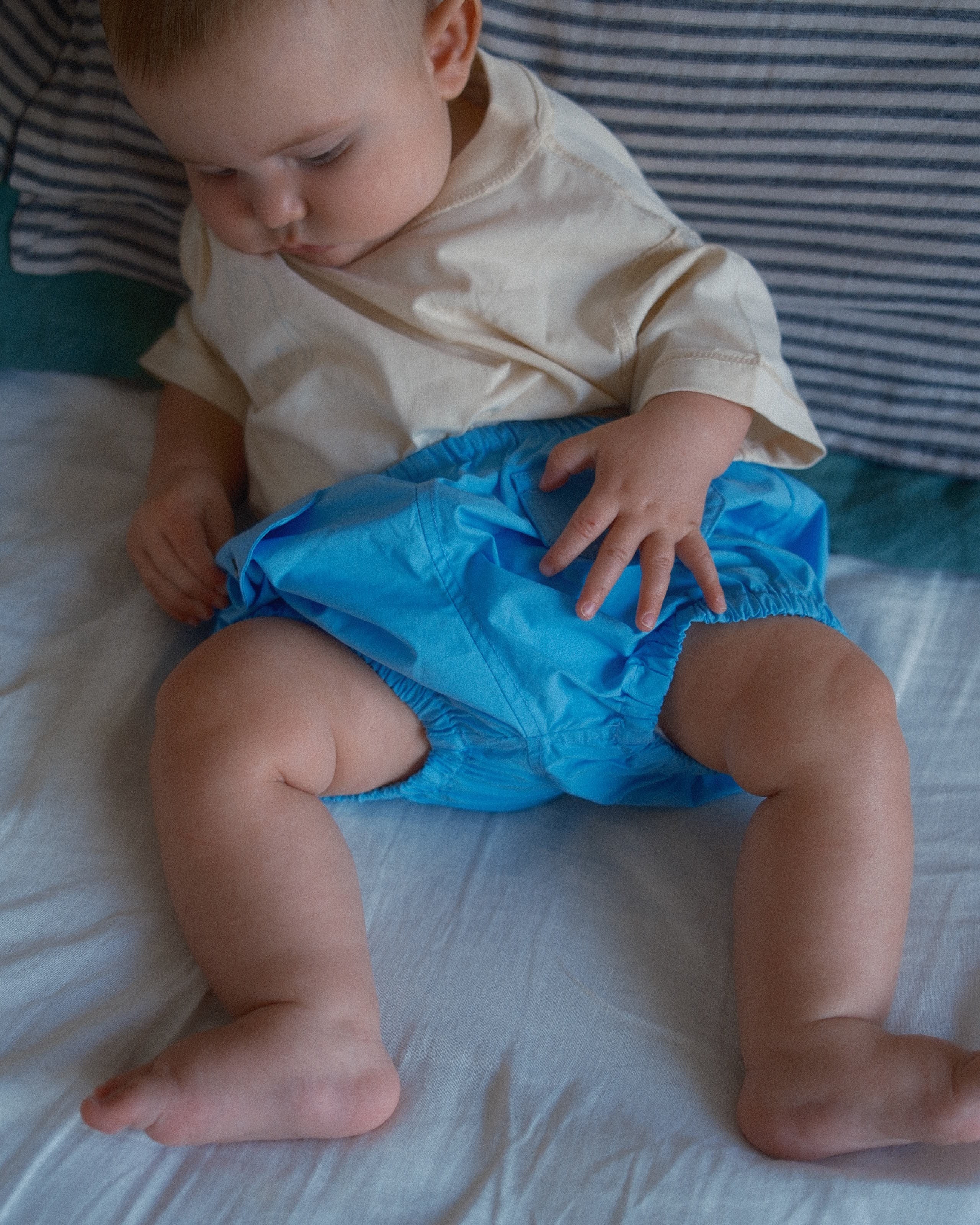 Baby wearing a blue diaper on a white surface